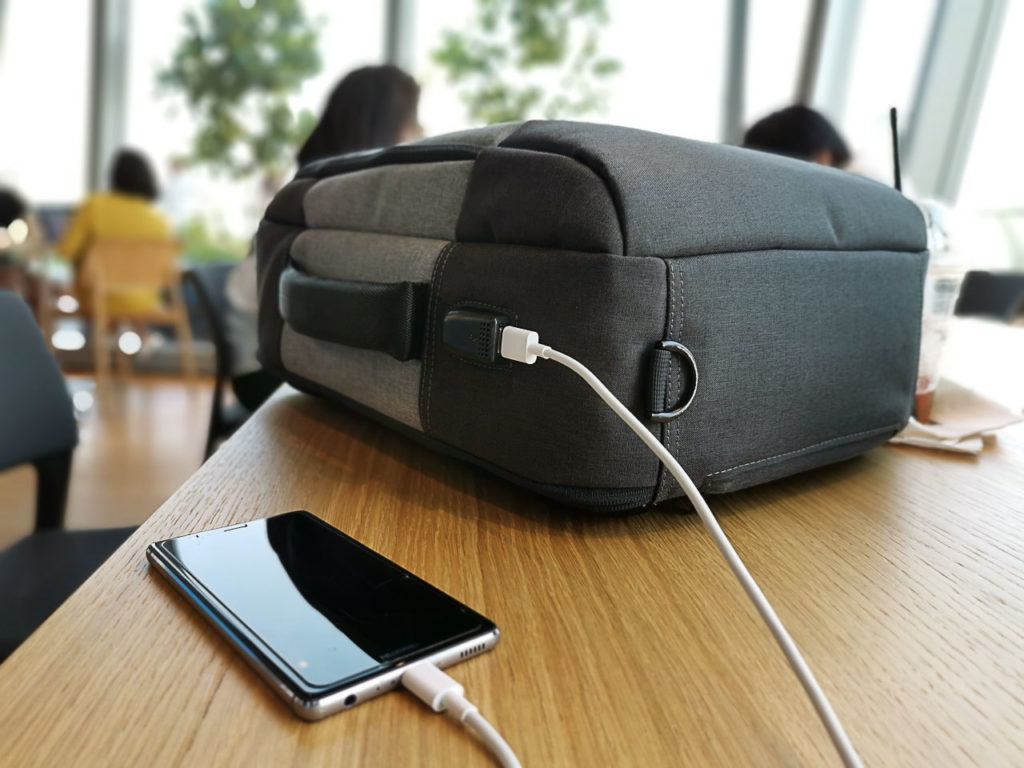 This modern daypack has a USB port on the outside which is connected to your power bank inside of it.