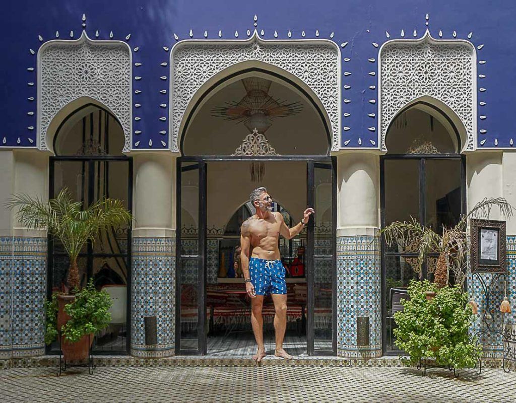 Homem desfrutando piscina em um Riad em Marrakech usando um short de secagem rápida sugerido como um bom presente de viagem masculino.