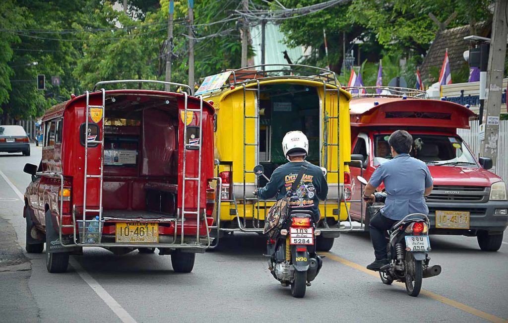 Foto de dois songthaews, espécie de ônibus tailandeses que circulam nas cidades ou entre aldeias.