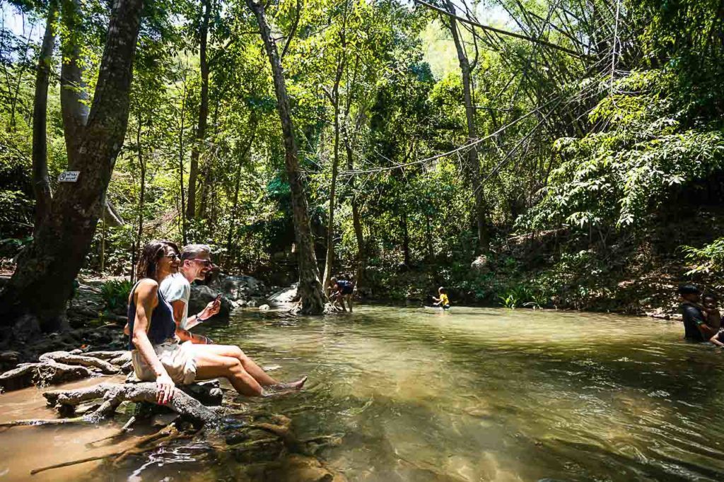 Viajantes e moradores locais se divertindo em uma piscina natural na Cachoeira Sai Yok.