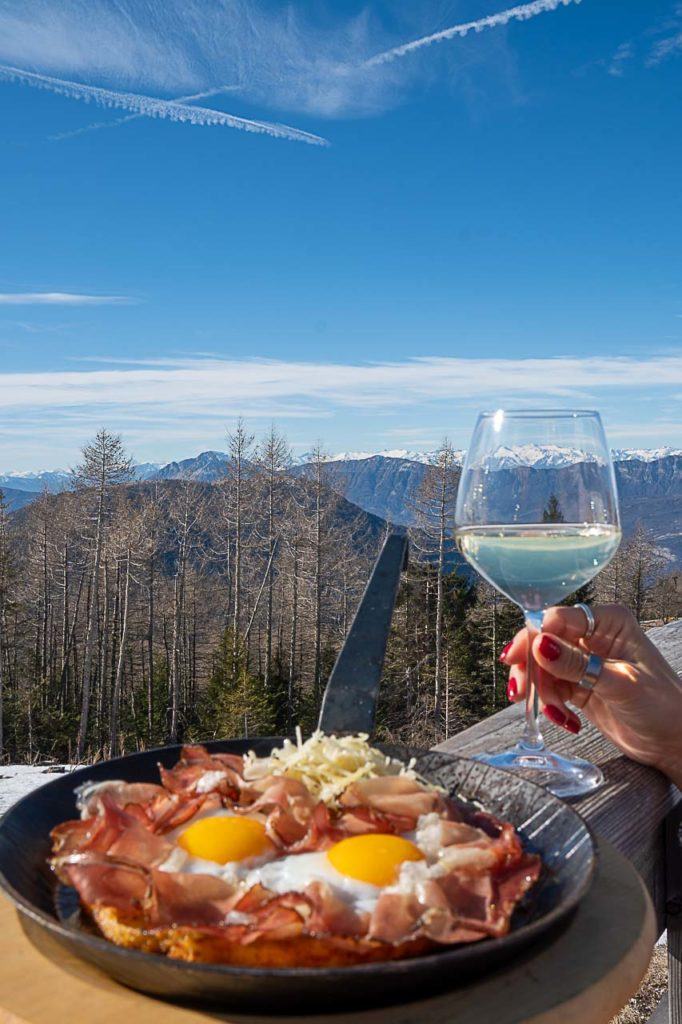 Padella Rustica, um copo de vinho e uma bela vista da montanha do Rifugio Baita Tonda, um restaurante imperdível em Folgaria.