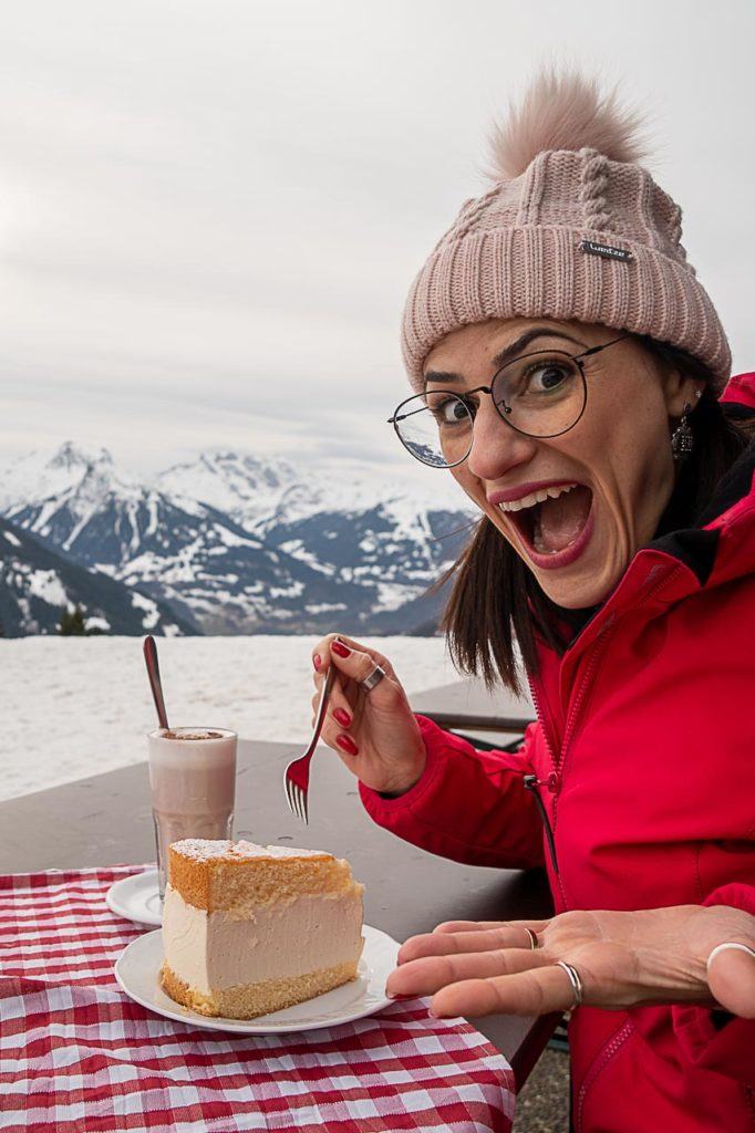 Mulher com uma fatia de Cheesecake após praticar esqui em Montafon.