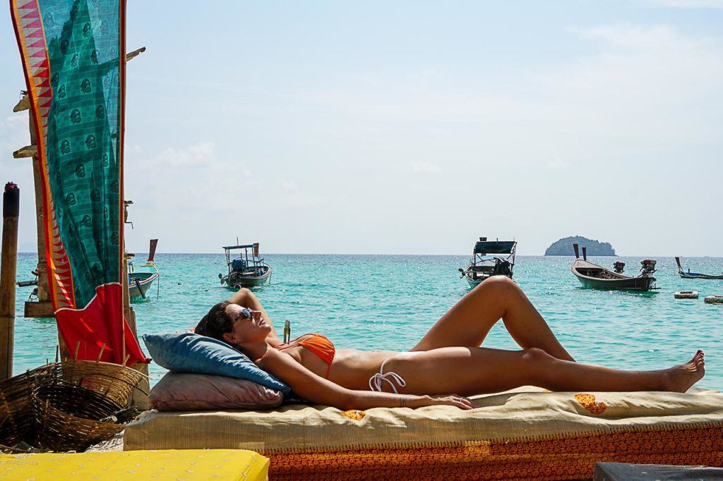 Woman sunbathing on Sunrise Beach and thinking about what to do in Koh Lipe at night.