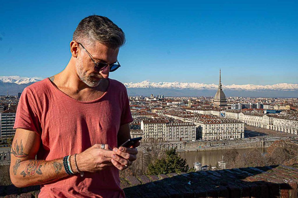 Homen anotando no celular os gastos de viagem na Europa. 