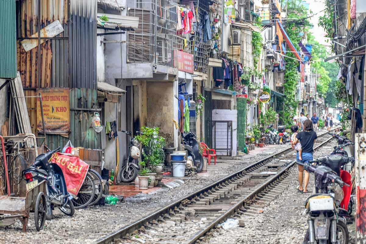Photo of a train track in between houses and buildings. It's one of the famous attractions in Hanoi, Vietnam.