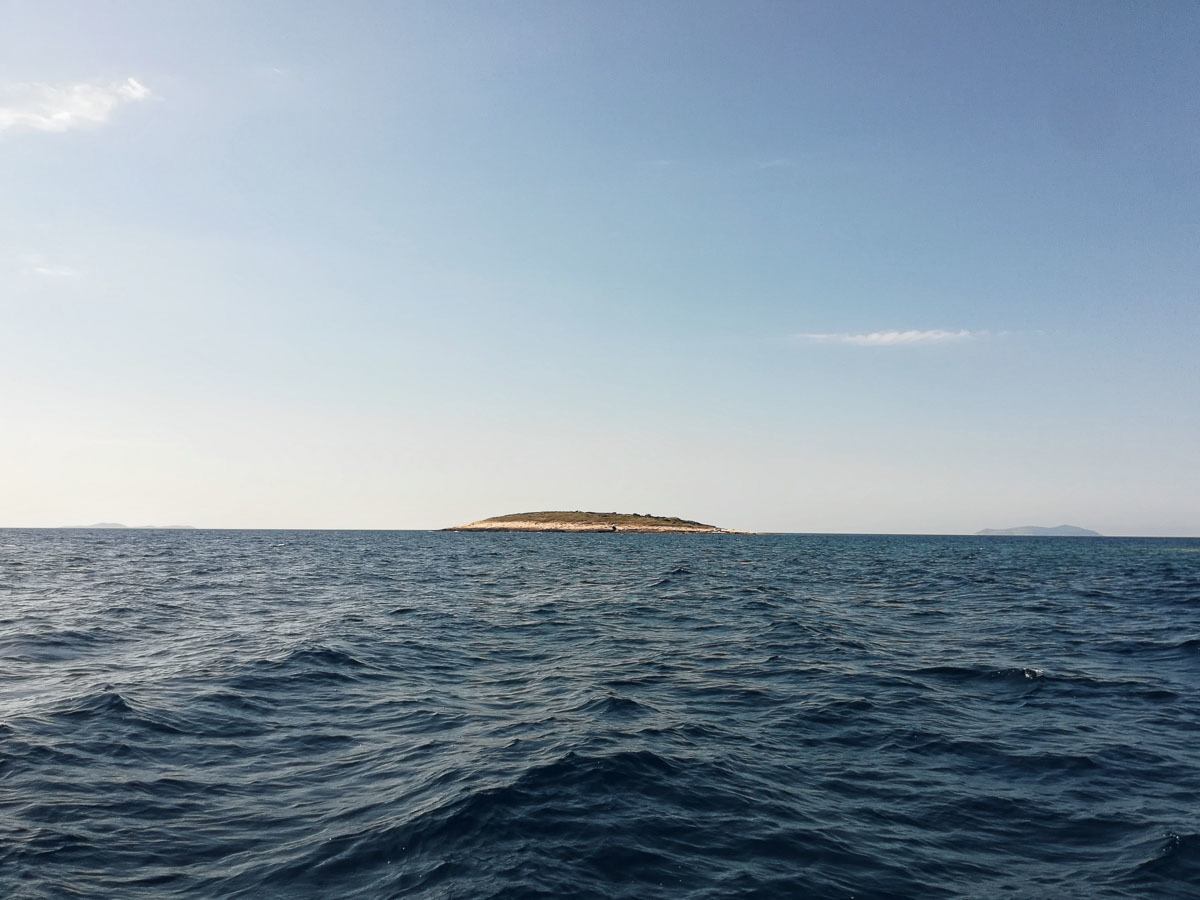 Photo of a small island surrounded by the deep blue sea. The photo is from Croatia.