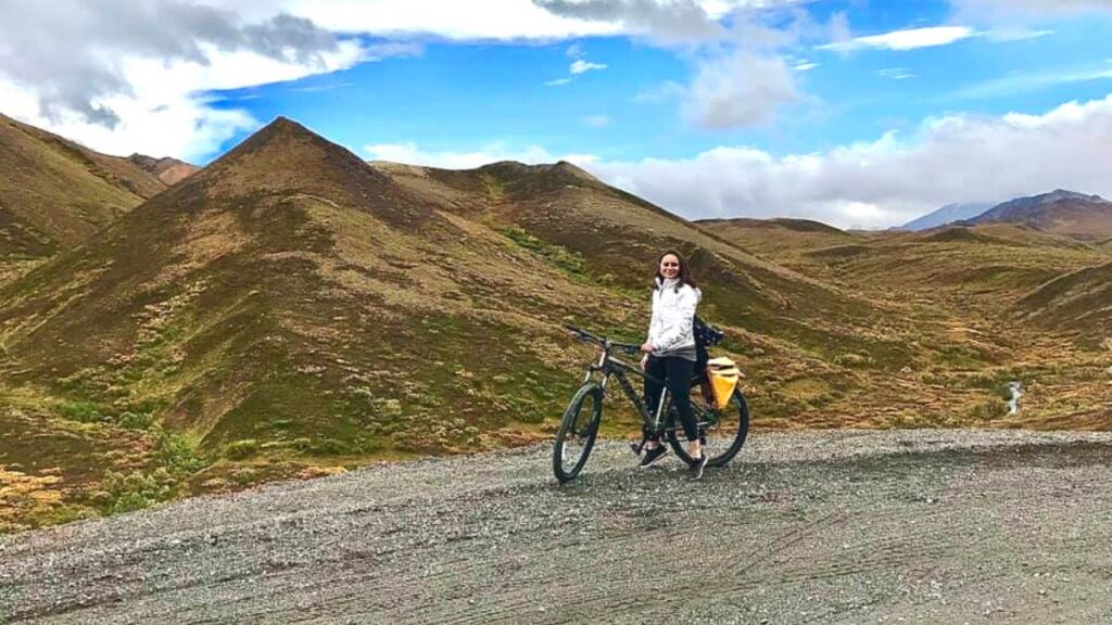 Photo of a woman on a bicycle at Denali National Park & Preserve. One of the top things to do on an Alaska road trip. 