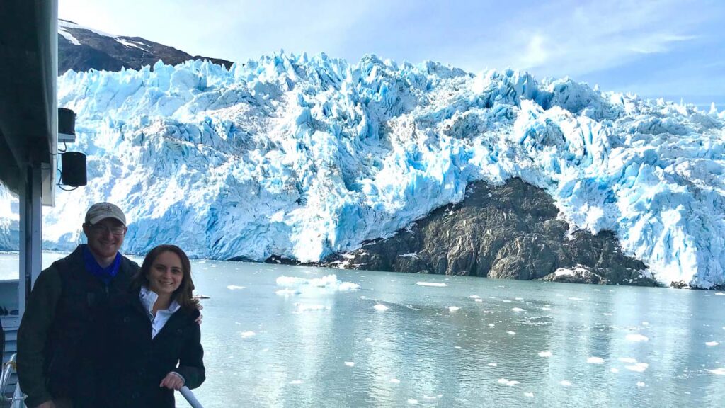 Photo of a couple posing during a day cruise in Alaska. One of the many boat tours in the Kenai Peninsula where you see the glaciers.