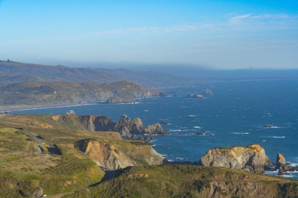 Photo of a coast hiking in California. It's a trail in Sonoma County showing the Pacific Ocean and the impressive rock cliffs near the water. 