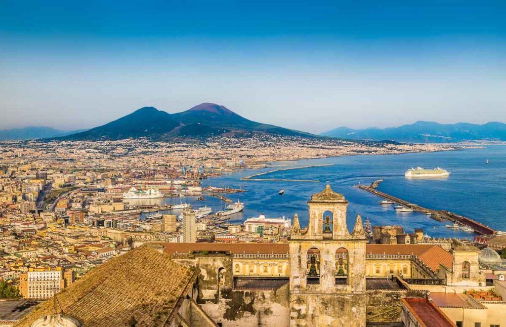 Scenic picture-postcard view of the city of Naples with famous Mount Vesuvius in the background in golden evening light at sunset, Campania, Italy.