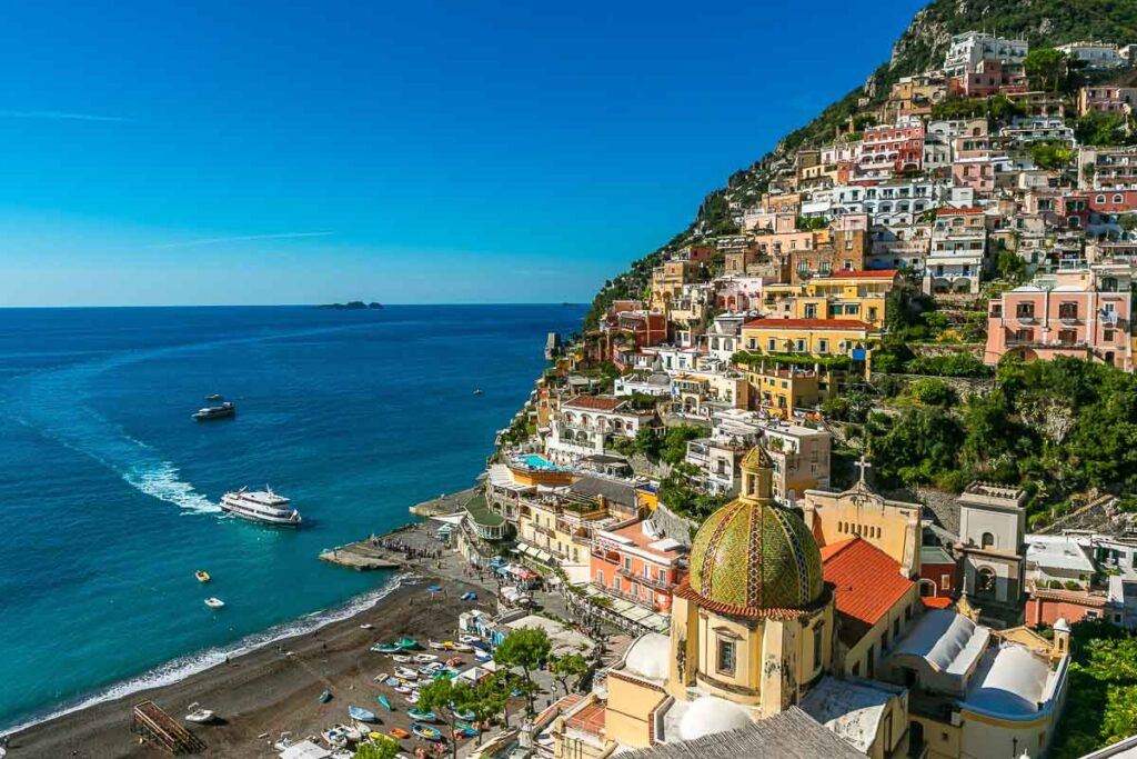 Photo of Positano town on the Amalfi Coast in Italy. Shows the houses on the cliff and its beach with turquoise water.