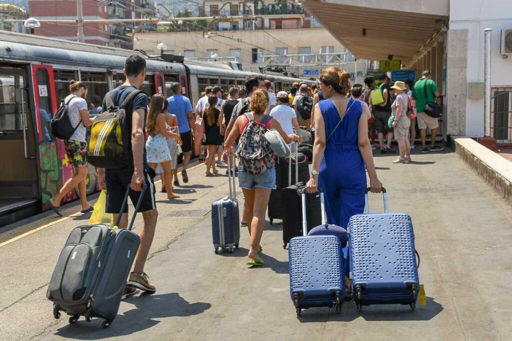 People pulling suitcases along a platform after arriving at Sorrento railway station.