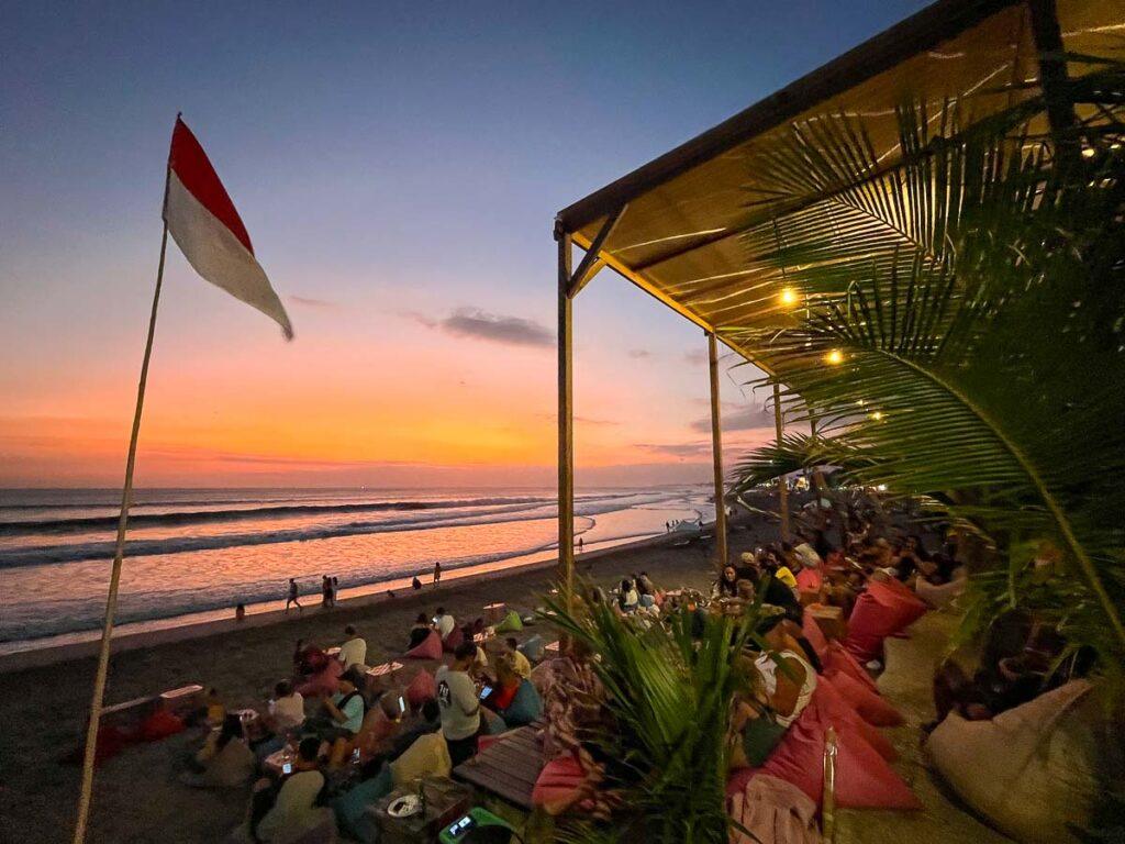 Photo of a beach bar in Canggu, Bali. The beanbags are laid out on the beach, and people go there to watch the sunset.