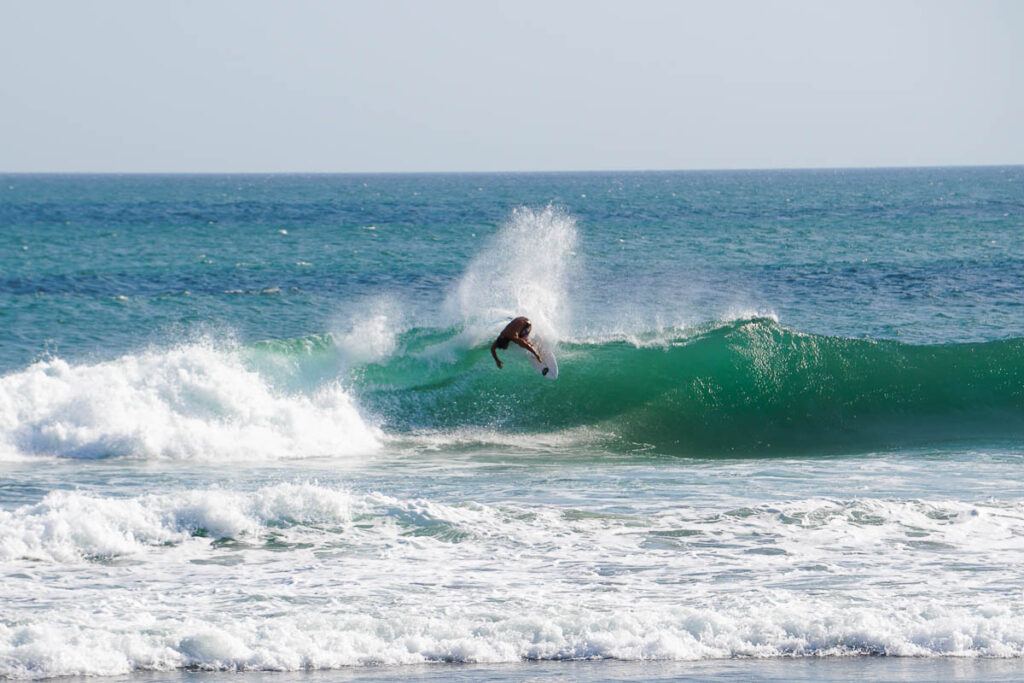 A surfer catching a wave in Canggu, Bali. Canggu is one of the best places to stay in Bali for digital nomads.