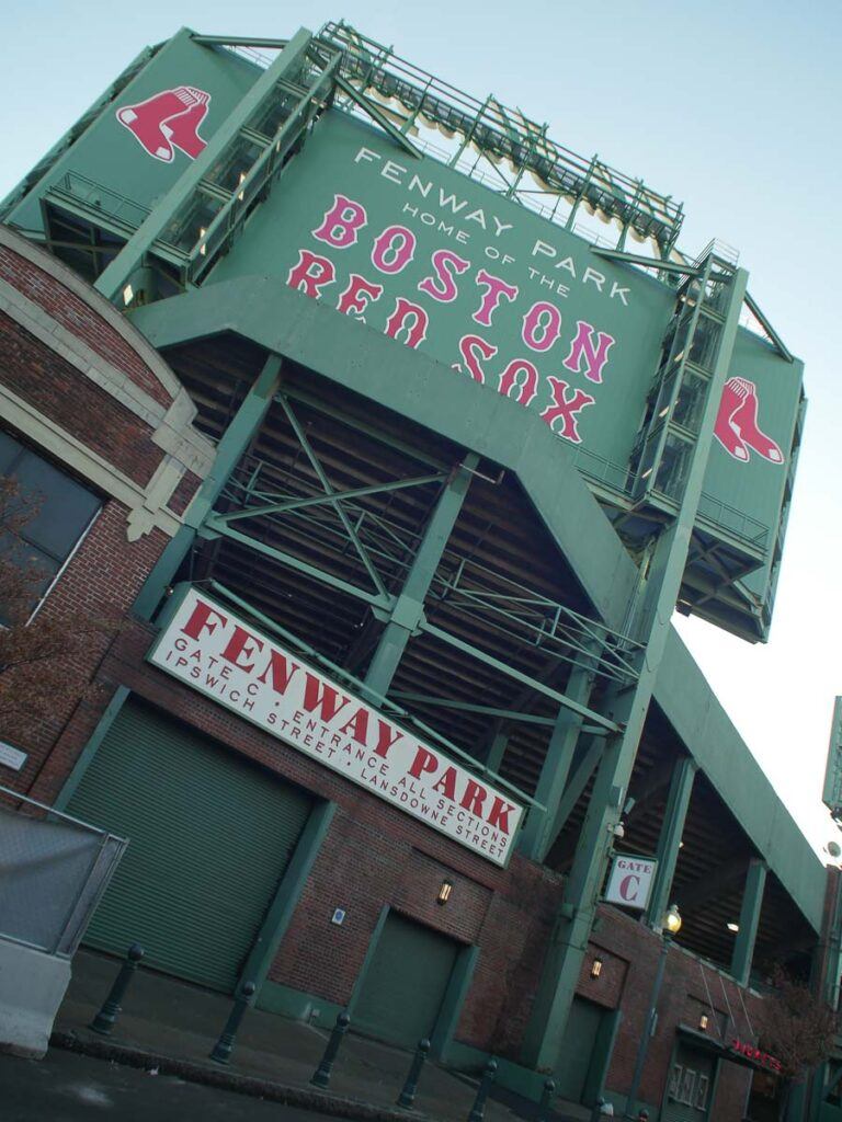 Photo of the Fenway Park facade with a big sign of the Red Sox baseball time on top of the wall.