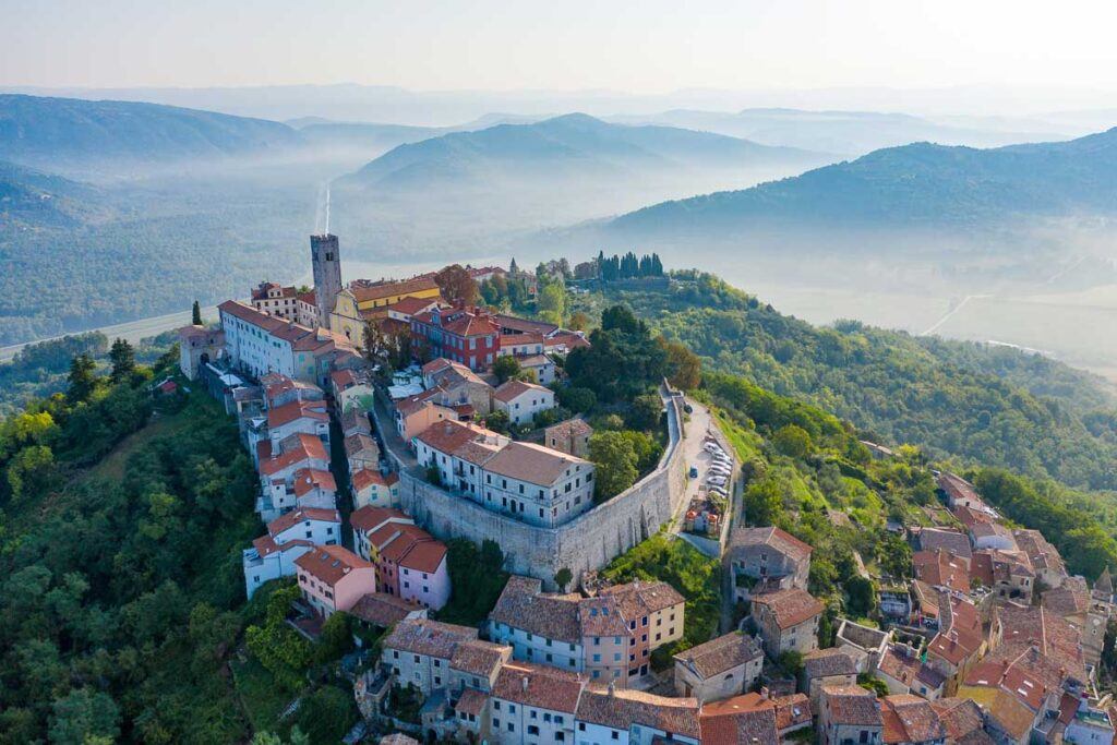 Ancient city Motovun on top of the mountain. The city is surrounded by a fortress wall. The background image are mountains and fog at the foot of the mountains. Istria, Croatia. The view from the drone. Selective focus.