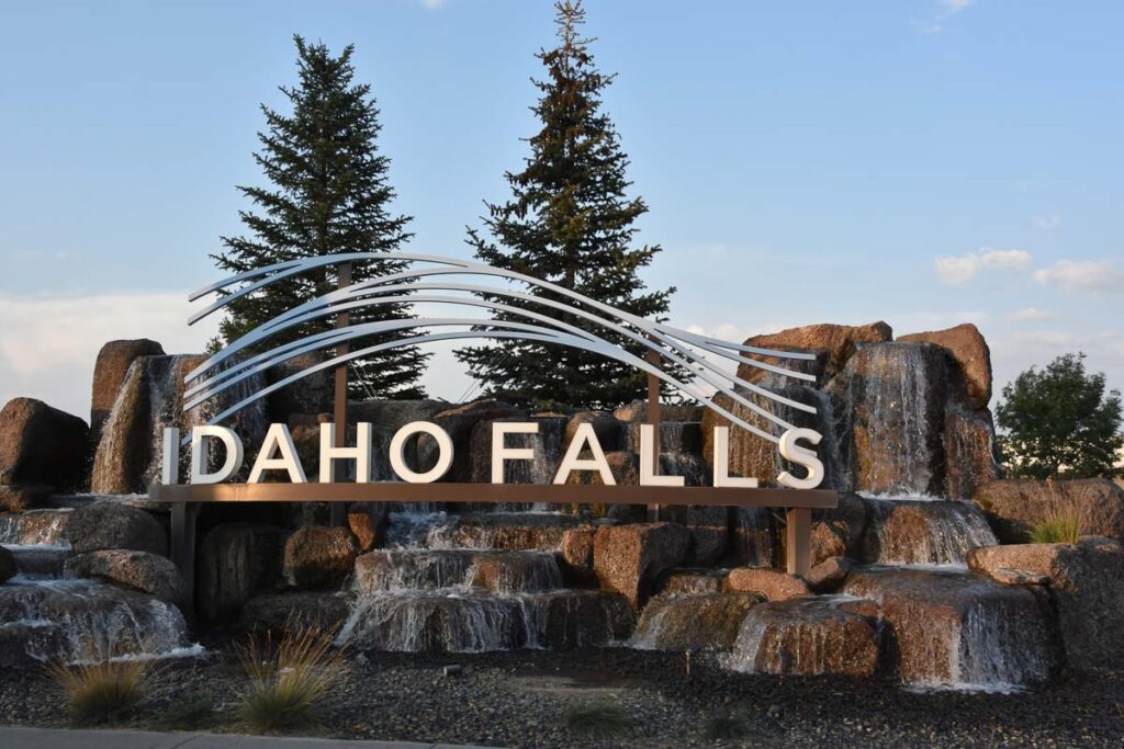 Sign of Idaho Falls' name over the rocks of a waterfall. There are many things to do in Idaho Falls and many are related to nature. 