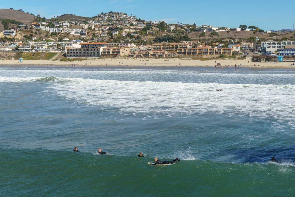 Pismo Beach is perfect for surfing. You can see many surfers in the water and the Pismo Downtown in the back. 