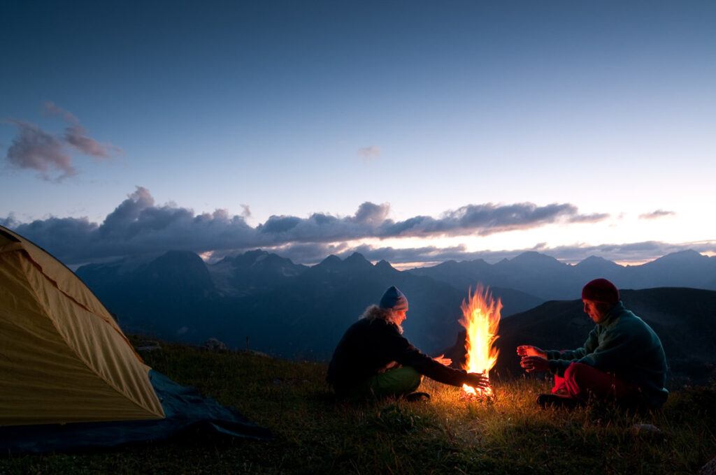A couple is camping in the wilderness, probably on a road trip in the US. Wild camping is an excellent way to road trip on a budget. 