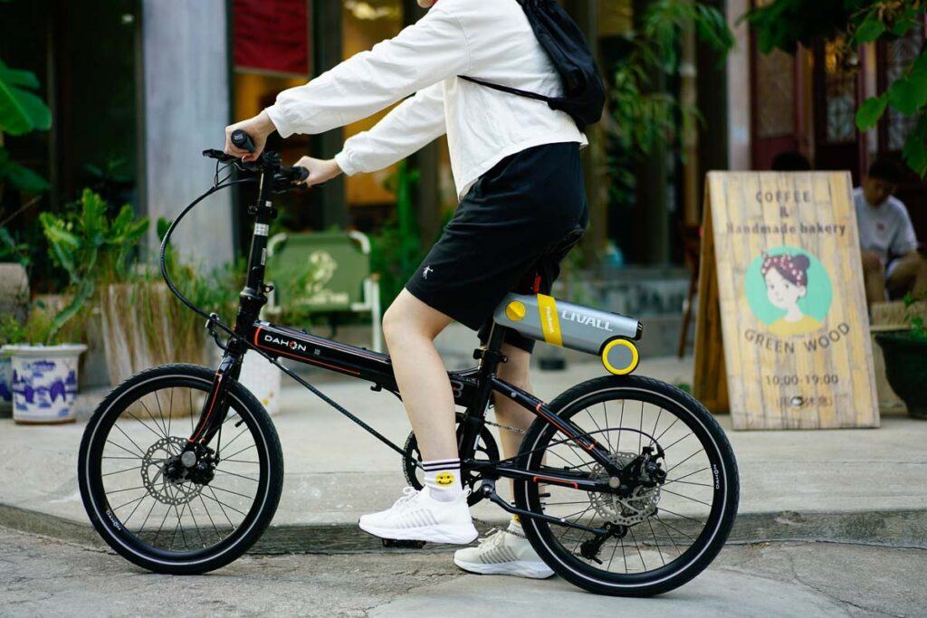 Um homem está pedalando em uma bicicleta dobrável com um kit de conversão de e-bike instalado. 