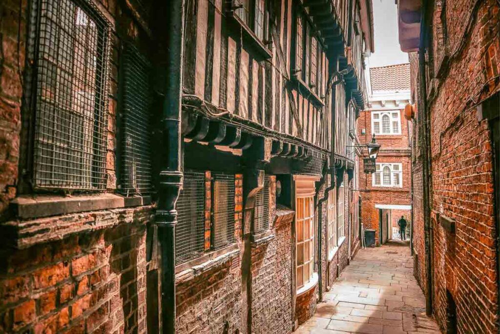 Photo of a medieval alley in York, England. You can see the houses made of red bricks and timber.