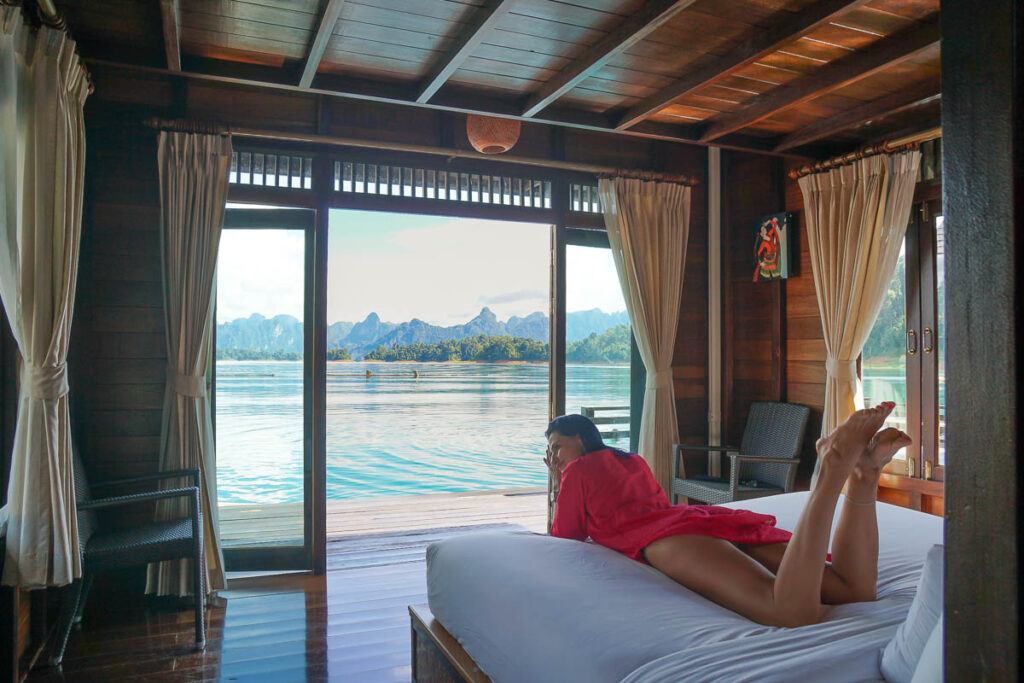 Woman laying in a bed of a floating bungalow at Khao Sok National Park in Thailand. She looks very relaxed.