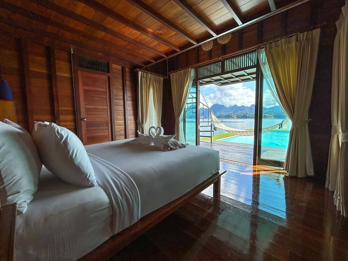 Photo of the bedroom of the Honeymoon Suite that shows the king-size bed with a lake view and the private pool in front of the bungalow.