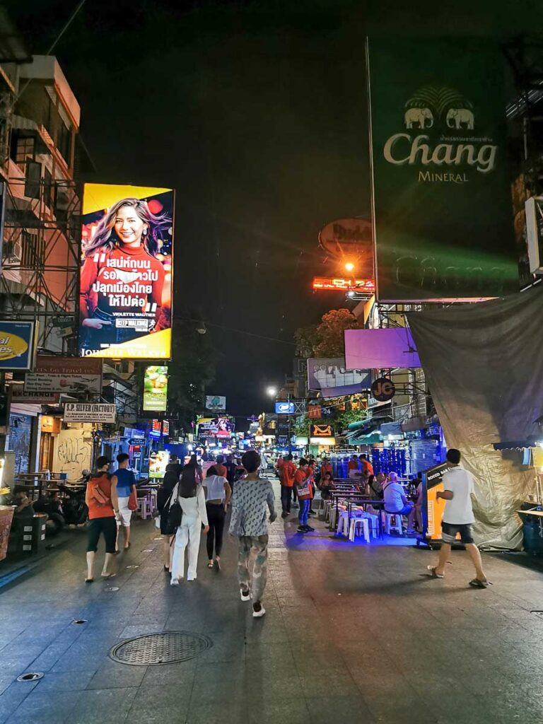 Is Bangkok safe to party? It generally is. This photo shows Khaosan Road, one of the famous places for parties and drinking. You can see young people walking around and a lot of bar signs.
