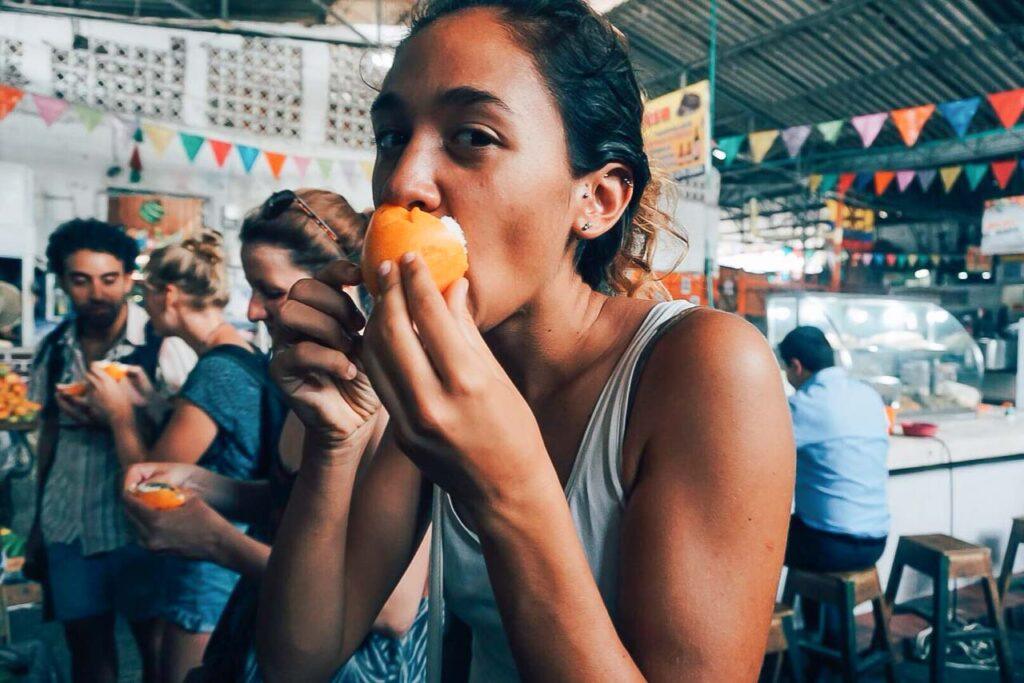 Woman trying a local Colombian fruit that looks like an orange by tastes like a kiwi. 