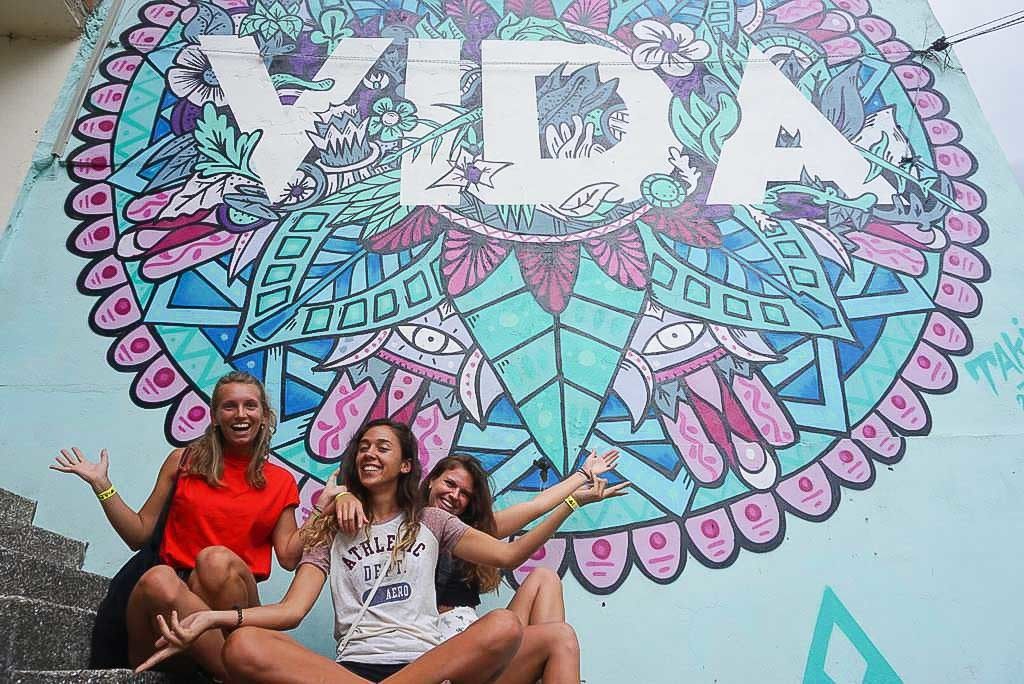 Three women sitting in front of graffiti art in Colombia.