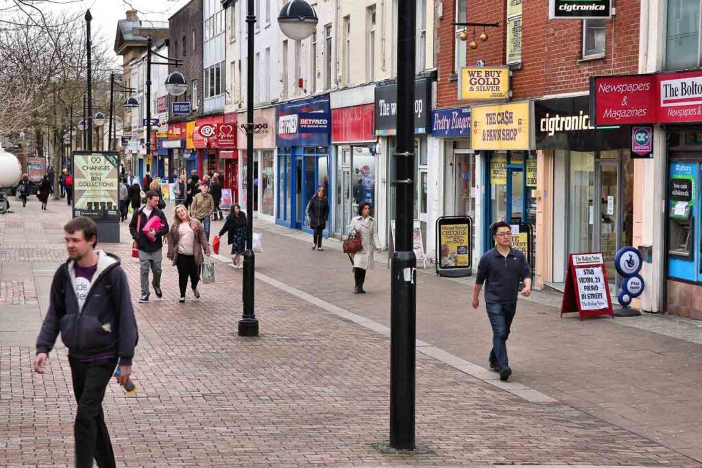 People walking along a shopping street in Bolton, UK. Bolton is part of Greater Manchester, one of the largest population areas in the UK.