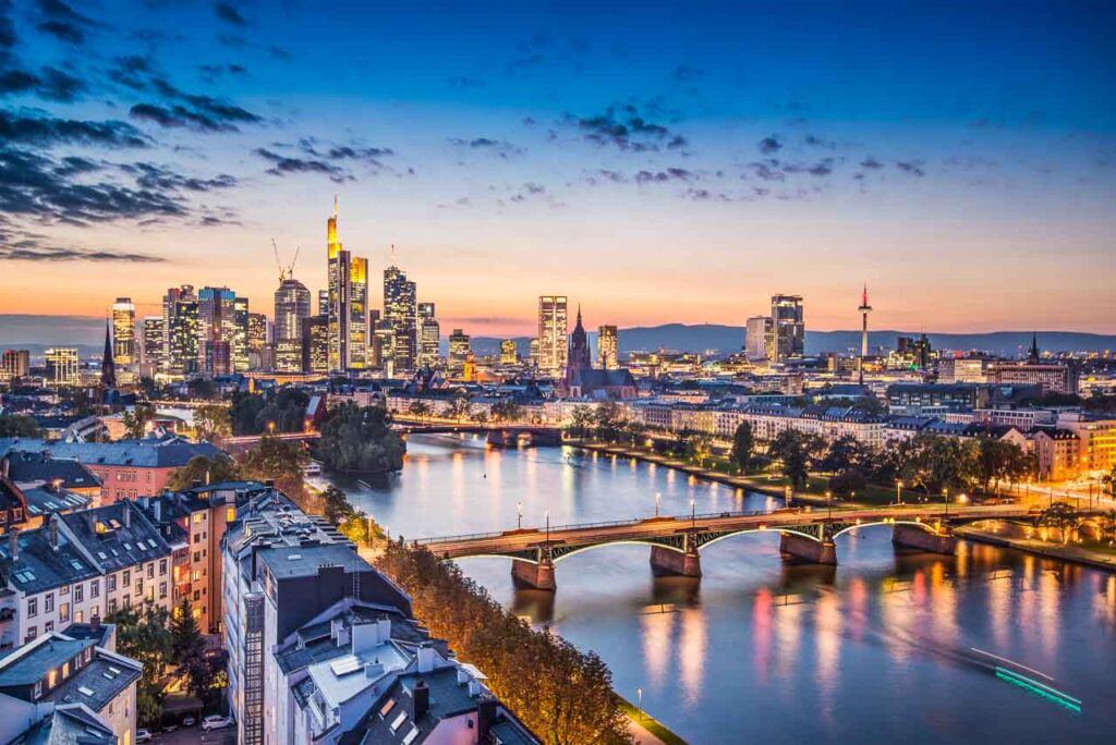 Photo of the sunset over Frankfurt, Germany. It shows the city skyline and the river.