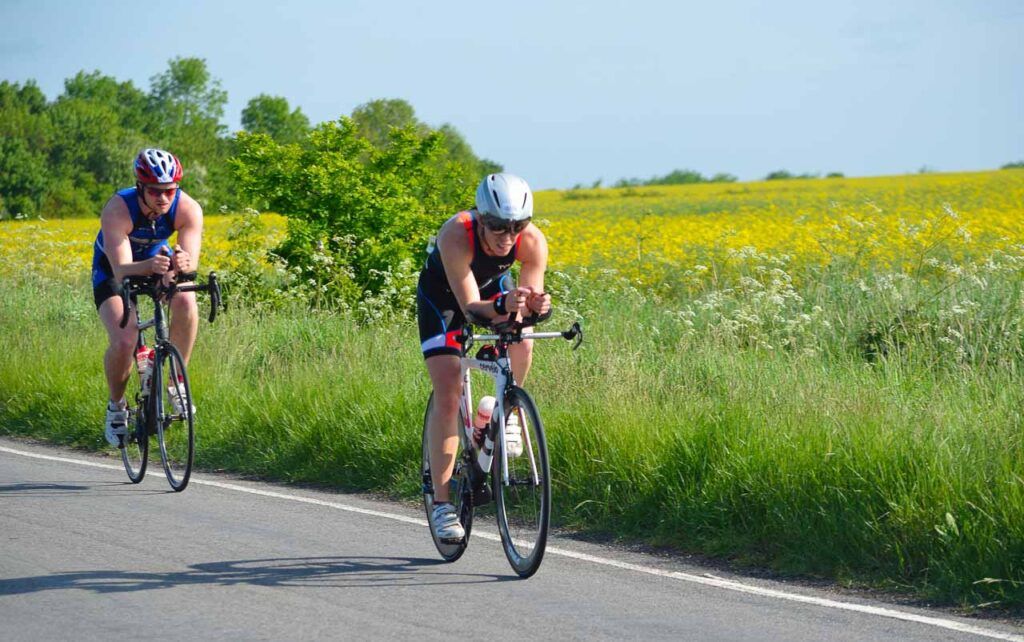 Two athletes competing Bolton Ironman in the UK. They are cycling together on an open road. 
