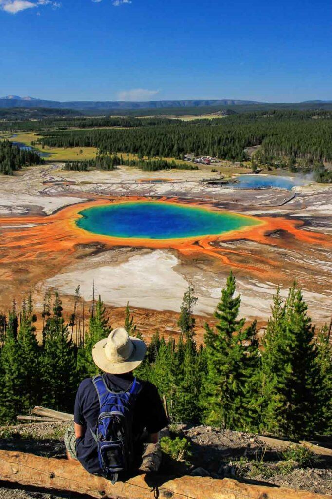 Man on a view point facing Yellowstone's grand prismatic spring. It's one of the most visited parks on the west coast of the United States.