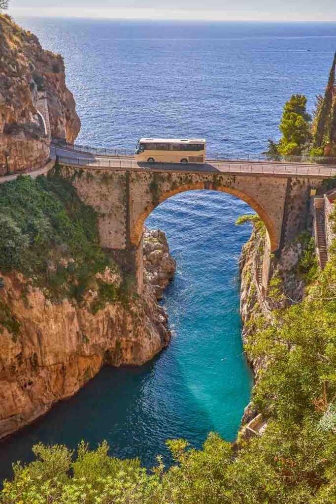 a bus driving over Furore road bridge on the Amalfi Coast. Here is one of the famous beaches you must add to your Amalfi Coast Itinerary. 
