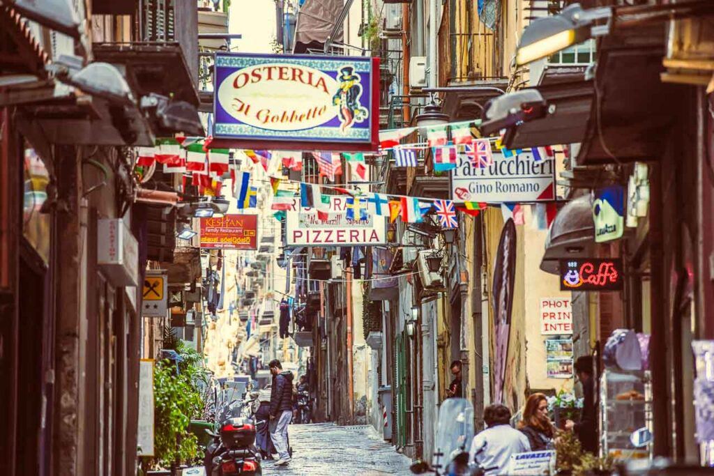 Small street with signs of restaurants, bars and cafes in Naples, Italy.