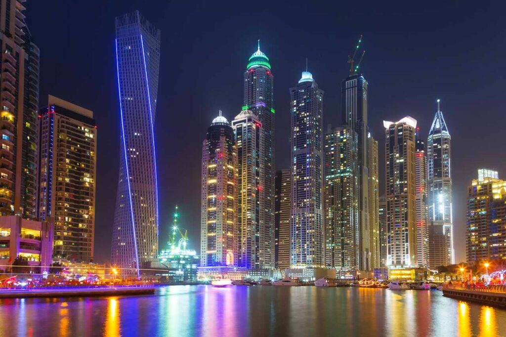 Dubai at night with lights reflecting in the water of Dubai Marina. The city has many tourist attractions, but you should also discover the hidden gems in Dubai, EAU.