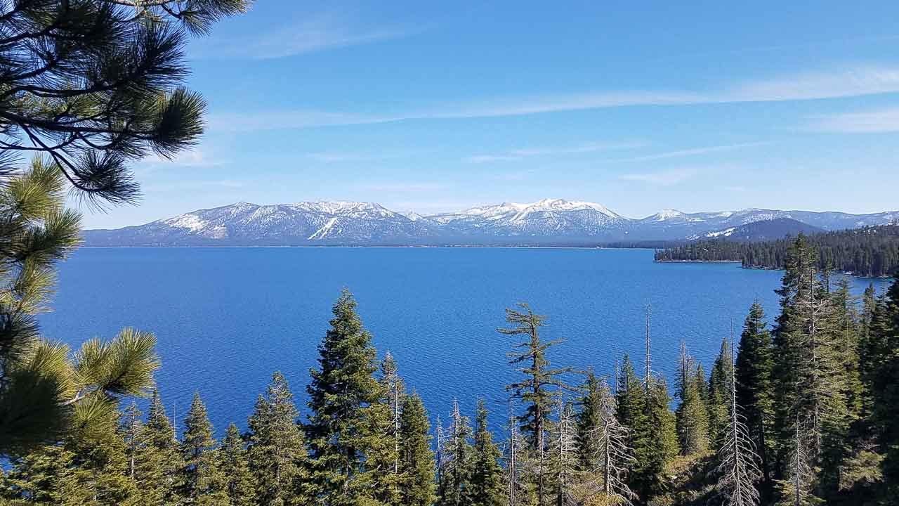 Photo of Lake Tahoe with snow-capped mountains in the background and pine trees in front of the lake. This is one of the best places to visit in Northern California for a weekend getaway.