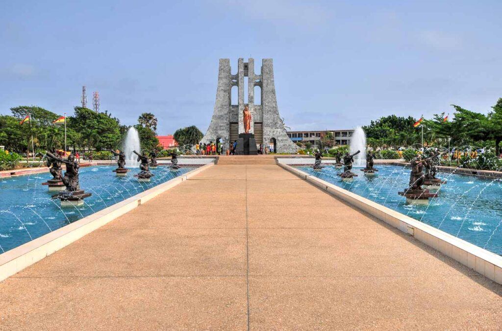 A view of Tourists in Kwame Nkrumah Memorial Park in Ghana. There are statues and a big monument.