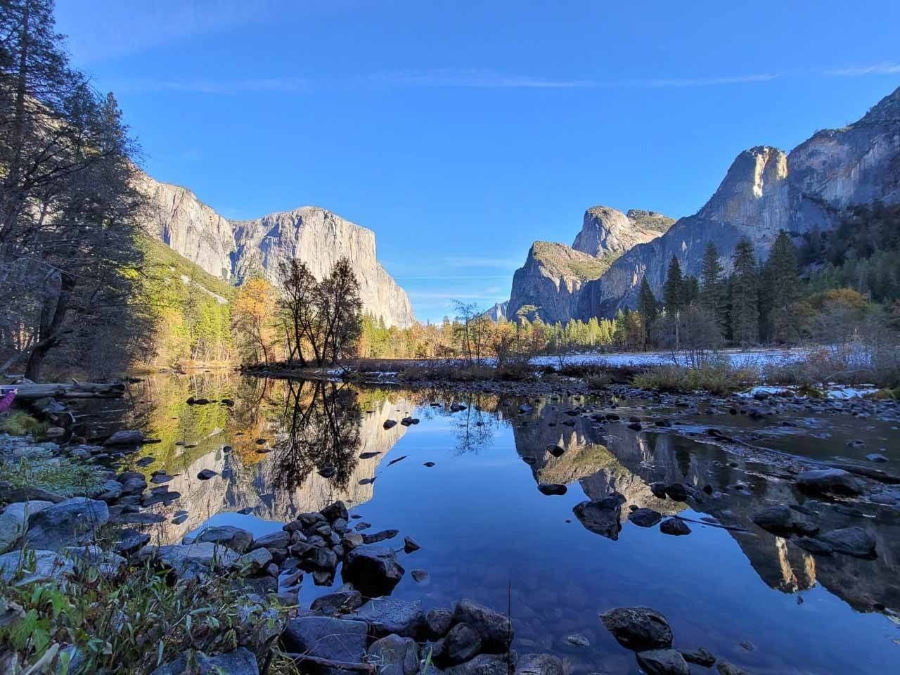 Photo of Yosemite National Park in Northern California, US. Shows the rocky mountains in the background and a lake in the front.