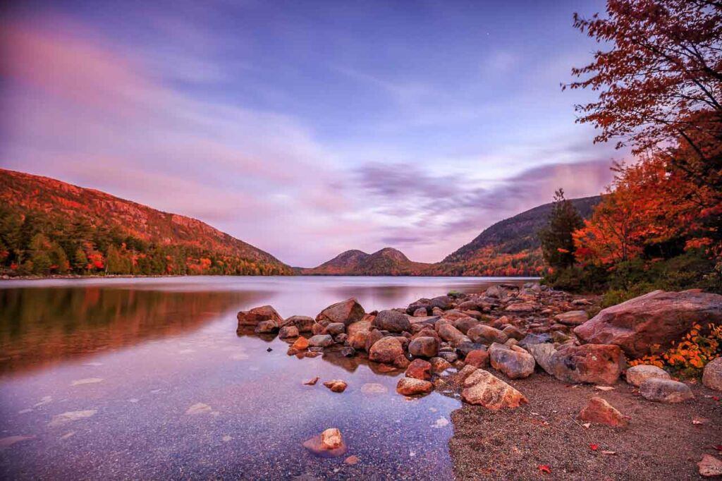 Photo of Jordan Pond in Acadia National Park, Maine, USA. It shows the body of water surrounded by hills.