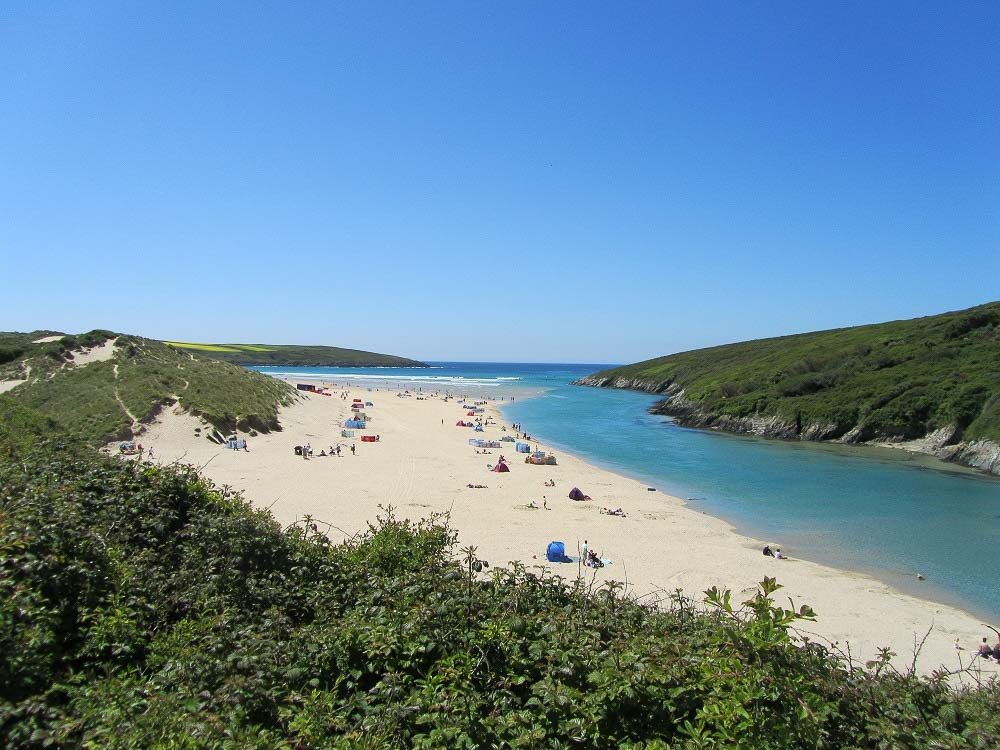 Crantock is one of the largest beaches in Newquay with soft sand. There are many people on the sand.