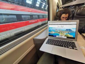 Woman working on her laptop in a train in Italy. She is a digital nomad worker.
