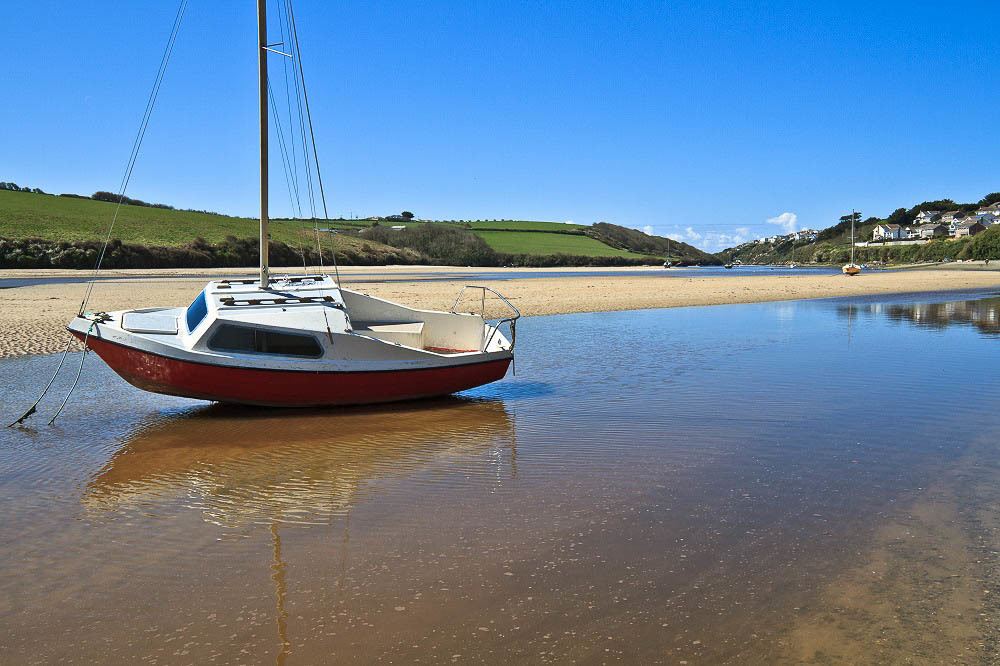 Gannel Estuary Beach in Newquay is a great place to go kayaking and canoeing. The photo is in low tide, you can see a boat stop in the middle of teh water stream.