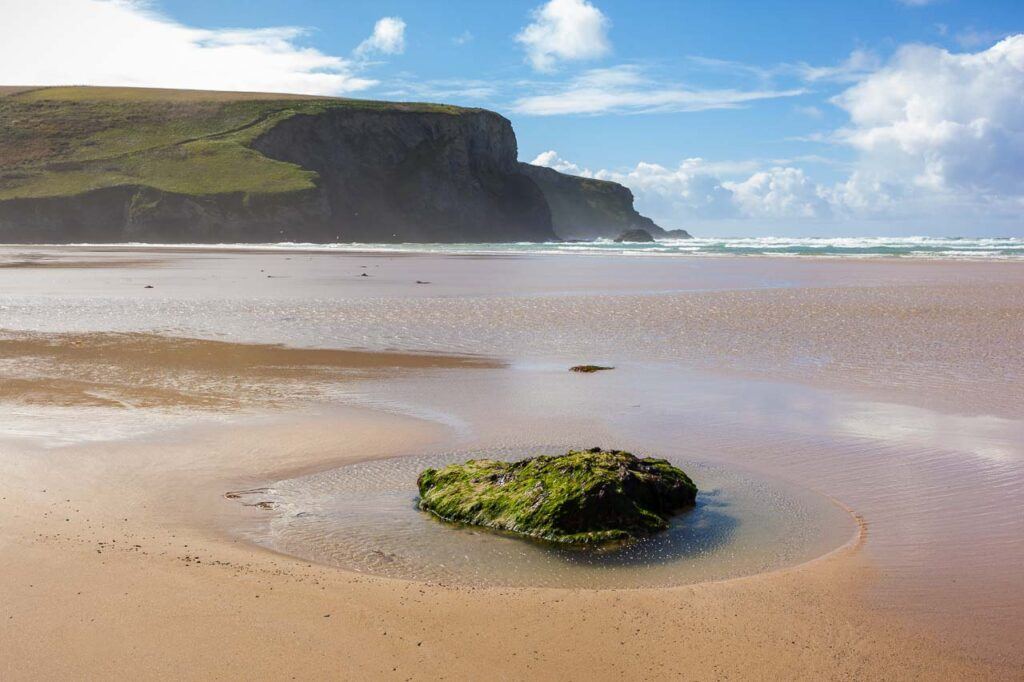 Beach at Mawgan Porth in Cornwall, UK. Huge cliffs in the background and crystal clear sea.