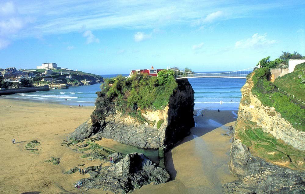 Towan Beach in Newquay has cliffs surrounding it and a rock island in the middle of the sand with a house on top and a bridge connecting to the mainland. It is one fo the famous beaches in Newquay.