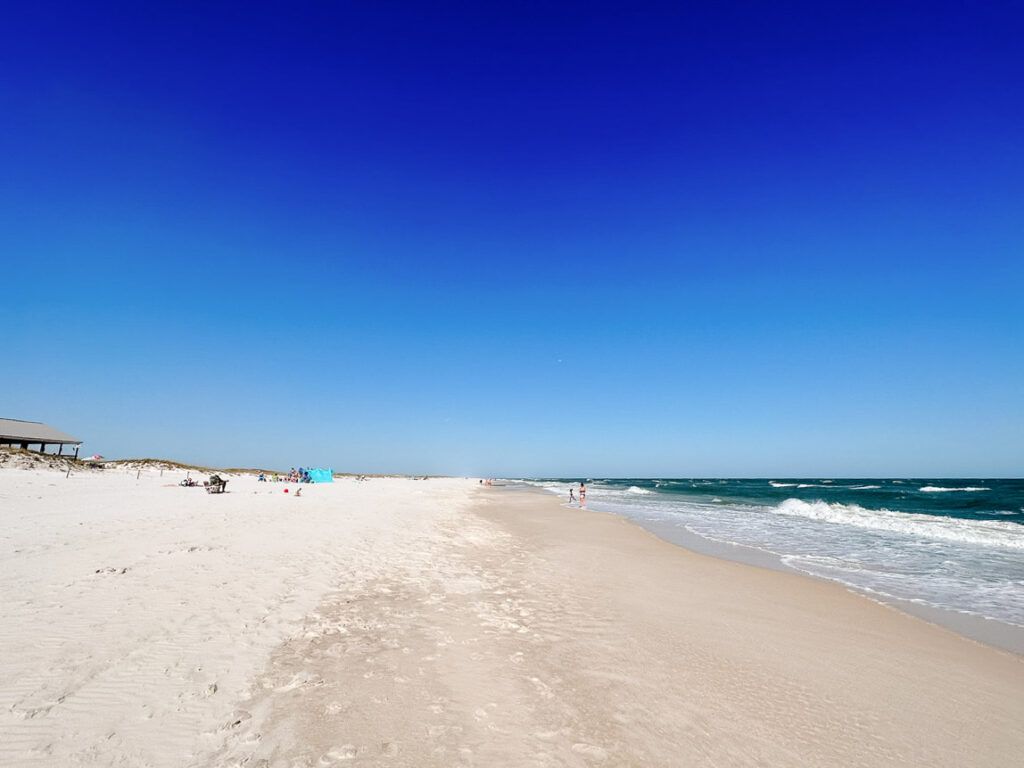 Photo of Panama City Beach in Florida, US. There are a few people on the sand and waves on the sea.