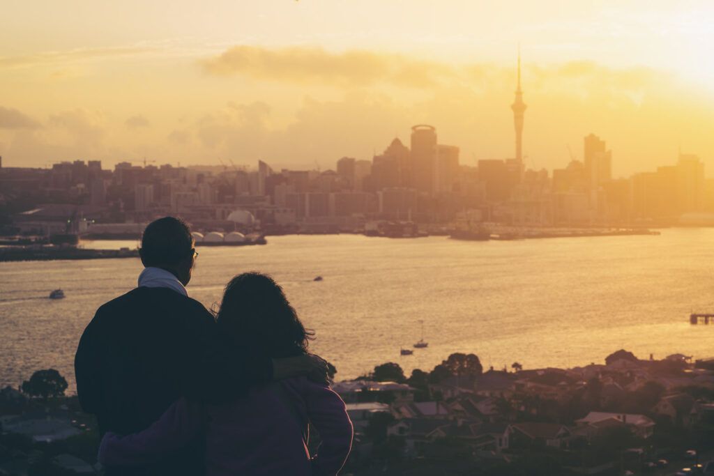 Happy couple watching sunset in Auckland. One of the romantic things to do in Auckland, New Zealand. 