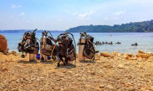 Photo of a beach in Havelock Islands with diving equipment on the sand and people learning how to scuba dive in the water.