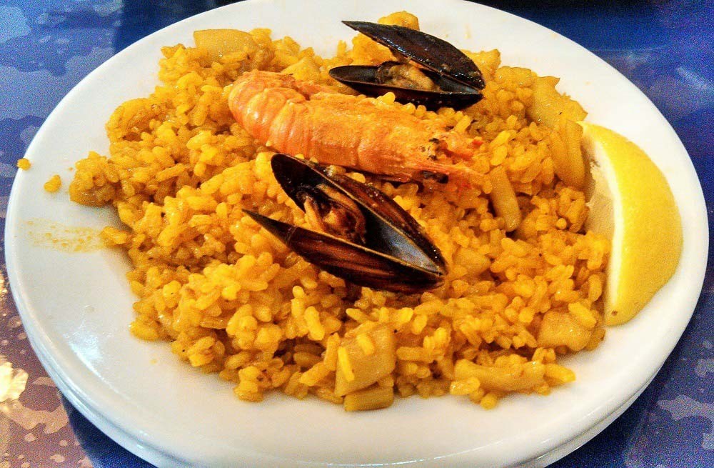 A plate of paella Valenciana. A typical rice and seafood dish you must try during your trip to Valencia, Spain.